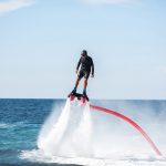 A rider on a flyboard in the ocean does difficult stunts