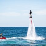 A rider on a flyboard in the ocean does difficult stunts