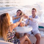 One young man and two beautiful woman drinking champagne and having fun on the boat