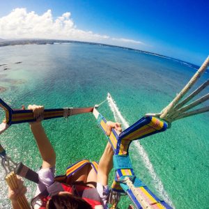couple parasailing with the speed boat